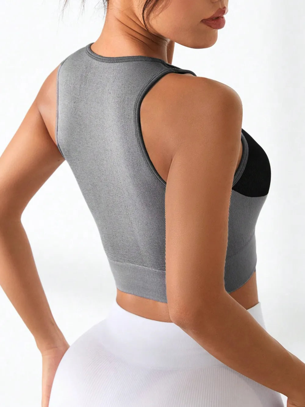 A female model back view wearing women’s fitness tank with a bold color block design and a round neckline