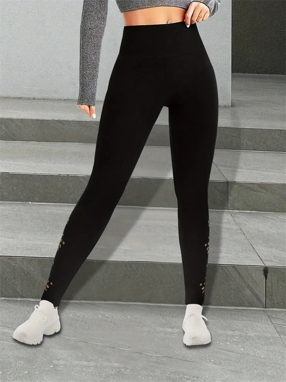 Person wearing black leggings with subtle floral cut-out design.