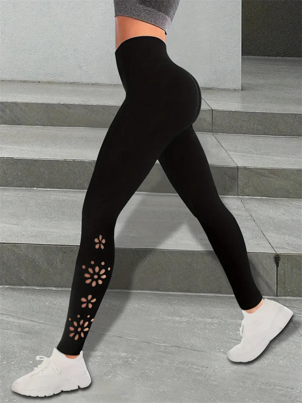 Person wearing black leggings with floral cutouts.